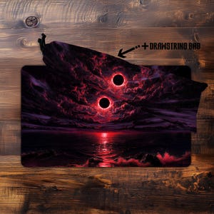 May include: A black and red gaming mousepad with a dramatic landscape design. The artwork features two large, glowing red orbs in a dark, cloudy sky above a reflective body of water. A matching drawstring bag is included.