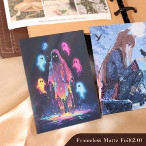 May include: Two rectangular art prints. The left print features a hooded figure in a colorful, dripping cloak surrounded by glowing neon ghosts in blue, pink, and yellow. The right print depicts an anime-style character with long hair in a snowy landscape.