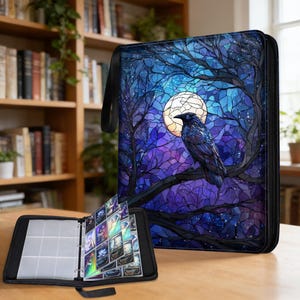 Könnte beinhalten: Schwarzer Kartenordner mit einem Raben- und Monddesign. Das Cover zeigt eine Buntglas-Illustration eines Raben, der auf einem Ast vor einem Nachthimmel mit Vollmond sitzt. Der Ordner ist geöffnet und zeigt Kartenhüllen.