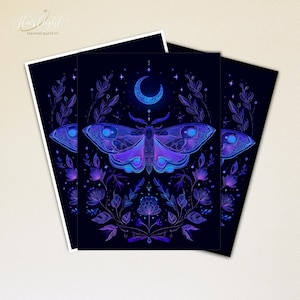 May include: Three art prints featuring a celestial moth design in shades of blue and purple against a dark background. The moth is centered, with a crescent moon above and floral elements surrounding it. The prints have white borders.