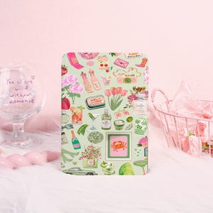 Peut inclure: Une coque de téléphone vert clair avec un collage d'illustrations à l'aquarelle. Le design comprend un téléphone rose, des fleurs, des cocktails, du parfum et un crabe encadré. L'étui a une esthétique fantaisiste et féminine.