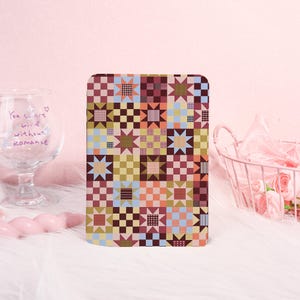 May include: A rectangular tablet case featuring a colourful quilt-inspired pattern of alternating star and checkered blocks in shades of brown, orange, yellow, blue, and pink. The design consists of a repeating grid of geometric shapes.