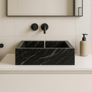 May include: A modern bathroom vanity with a black marble-look sink, black faucet, and a rectangular mirror. A beige soap dispenser sits on the white countertop. The walls are tiled in a neutral color.
