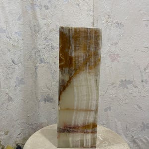 Puede incluir: Un jarr&oacute;n alto y rectangular hecho de &oacute;nix blanco y marr&oacute;n con un patr&oacute;n natural estriado. El jarr&oacute;n tiene un acabado liso y pulido.