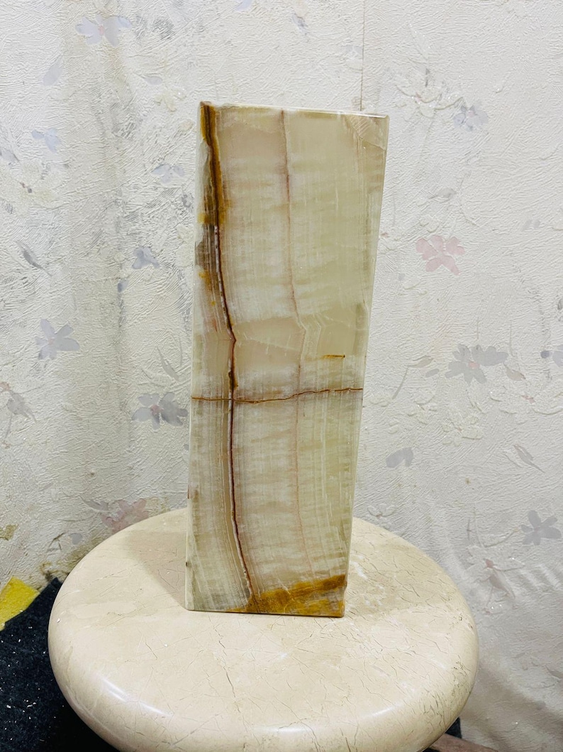 Puede incluir: Un jarr&oacute;n alto y rectangular hecho de &oacute;nix blanco y marr&oacute;n. El jarr&oacute;n tiene una superficie lisa y pulida y un patr&oacute;n natural y org&aacute;nico.