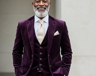May include: A man wearing a purple velvet suit with a white shirt and a beige tie. He is smiling and has a gray beard.
