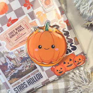 May include: A clear phone case adorned with autumn-themed stickers. Stickers feature pumpkins, falling leaves, and the text "hello FALL". Other text includes "hello AUTUMN", "COSY BOOK GIRLIE FALL", and "ANNUAL AUTUMN FESTIVA STARS HOLLOW".