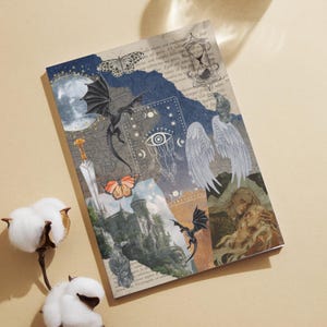 Pode incluir: Caderno decorativo com um design de colagem com dragões, borboletas, um castelo e elementos celestiais. A capa tem uma estética vintage com uma mistura de ilustrações e texto, criando um tema de fantasia.