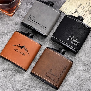 Könnte beinhalten: Vier personalisierte Flachmänner aus grauem, schwarzem und braunem Leder. Jeder Flachmann hat einen anderen Namen und ein anderes Datum eingraviert, einer zeigt eine Berg-Grafik. Ideal als Geschenk für Trauzeugen.