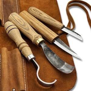 May include: A set of wood carving tools with wooden handles and metal blades, displayed on a brown leather roll. The set includes a curved gouge, a straight knife, and other specialized carving tools. The leather roll has pockets for each tool.