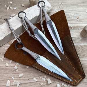 Handgeschmiedetes Wurfmesser-Set 3-teilig aus Kohlenstoffstahl, mit Paracord umwickelte Griffe, ausbalanciert für präzises Werfen, inklusive Lederetui.