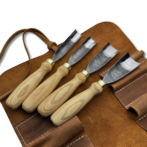 Può includere: Set di quattro sgorbie per intaglio del legno con manici in legno chiaro, puntali in ottone e lame in acciaio curve. Presentate in un astuccio in pelle marrone con cinturino.