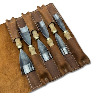 以下が含まれることがあります： 木製のハンドルと金属製の刃が付いた6つの木彫りノミのセット。個別の茶色の革鞘に収められています。ノミは、ツールを示すロールアップレザーケースに配置されています。