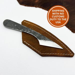 Kiridashi knife on leather sheath beside hide - carbon steel for wood and leather cutting.
