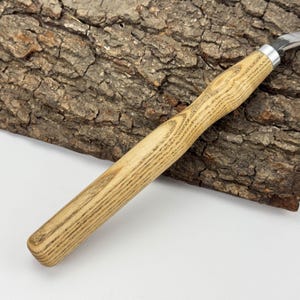 May include: A wooden handled carving knife with a stainless steel blade. The handle is made of light brown wood with a dark brown grain pattern.
