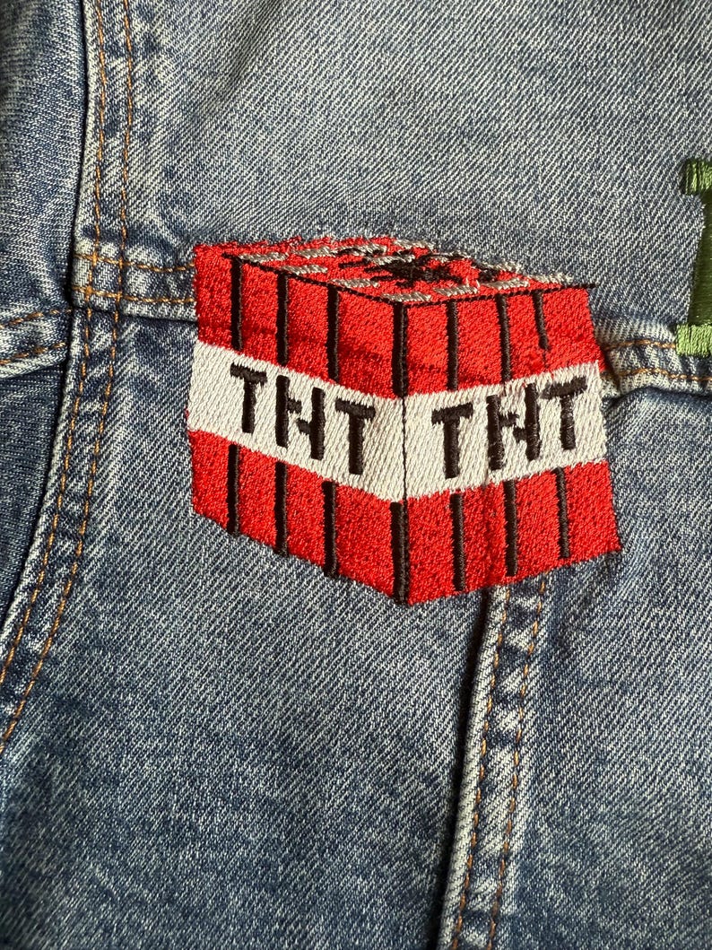 May include: A red and black embroidered patch of a Minecraft TNT block with the text "TNT" on the front.