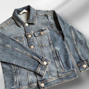 May include: A blue denim jacket with a button closure, two front pockets, and a single chest pocket. The jacket has a faded look and is made of a soft, comfortable material.