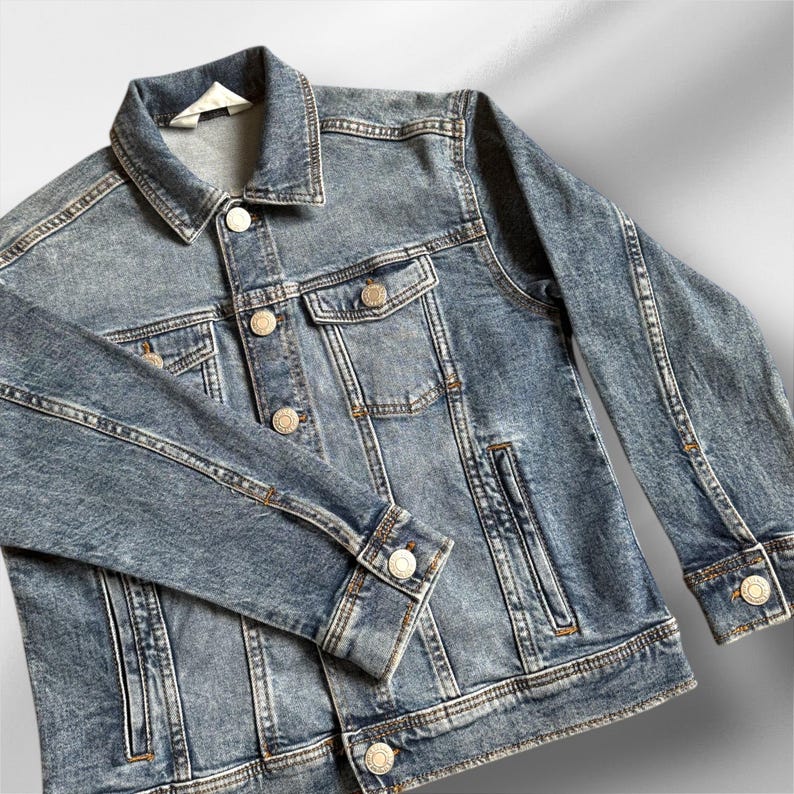 May include: A blue denim jacket with a button closure, two front pockets, and a single chest pocket. The jacket has a faded look and is made of a soft, comfortable material.