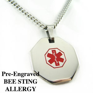 May include: A silver medical alert necklace with a red and white star of life symbol on a silver octagonal pendant. The pendant is pre-engraved with the text "BEE STING ALLERGY".