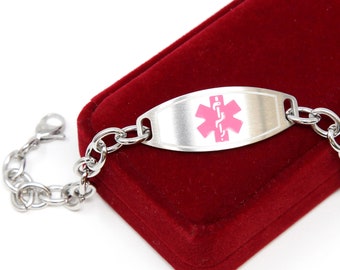 May include: A silver medical alert bracelet with a pink medical symbol and a chain link. The bracelet is in a red velvet box.