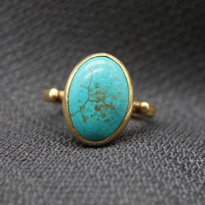May include: A gold ring with a turquoise oval gemstone set in a bezel setting.