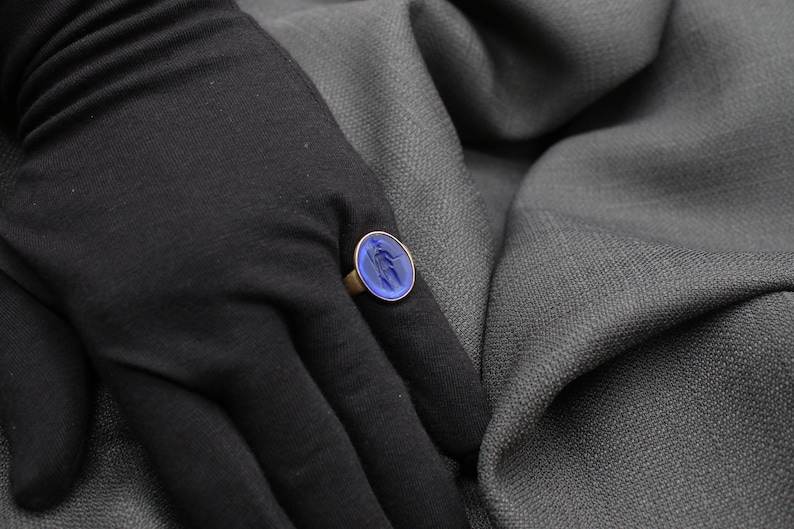 May include: A gold ring with a blue oval-shaped stone set in the center. The stone has a swirling pattern.