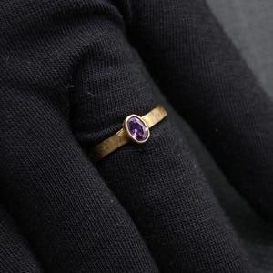 May include: A gold ring with a purple oval gemstone.