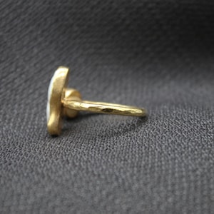 Puede incluir: Un anillo de oro con un dise&ntilde;o de esmalte blanco. El anillo tiene una textura martillada.