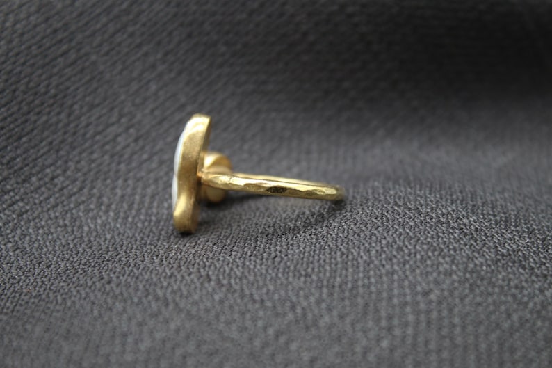 Puede incluir: Un anillo de oro con un dise&ntilde;o de esmalte blanco. El anillo tiene una textura martillada.