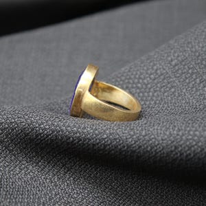 May include: A gold ring with a purple oval-shaped stone set in the center.