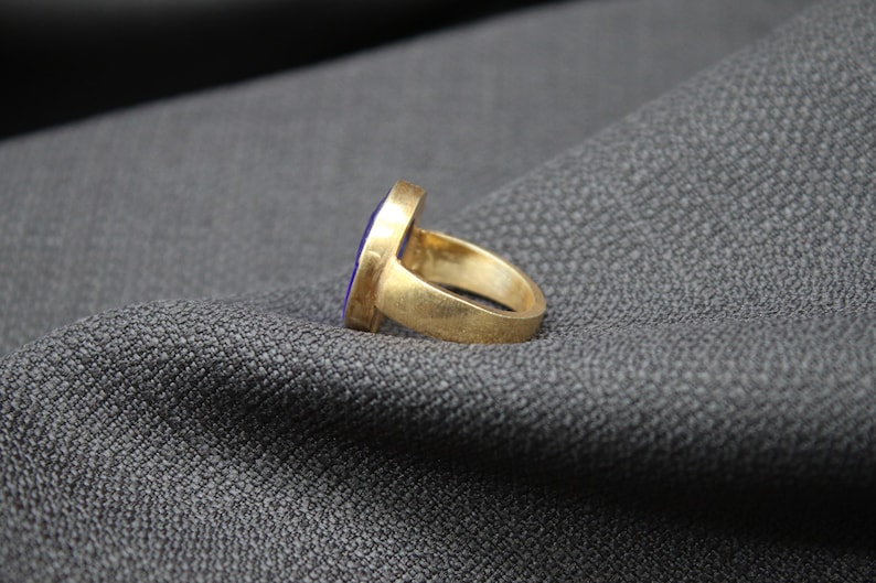May include: A gold ring with a purple oval-shaped stone set in the center.