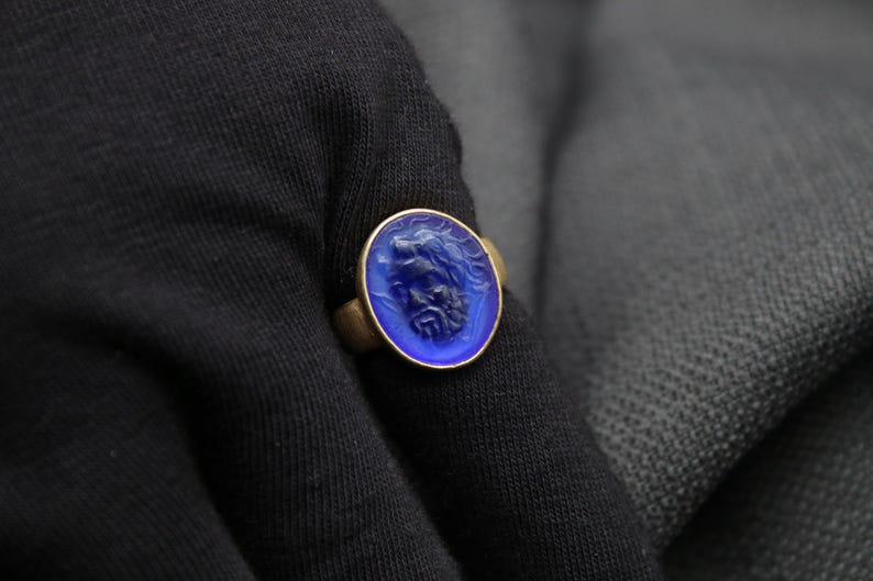May include: A gold ring with a blue glass cameo featuring a carved face.