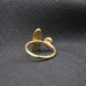 Puede incluir: Un anillo de oro con dos piedras en forma de l&aacute;grima. El anillo est&aacute; hecho de metal martillado y tiene un dise&ntilde;o simple y elegante.