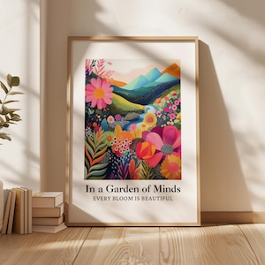 Könnte beinhalten: Ein rechteckiger Wandkunstdruck in einem hellen Holzrahmen mit einer farbenfrohen Landschaftsillustration aus Blumen und Bergen. Der Text lautet In a Garden of Minds und EVERY BLOOM IS BEAUTIFUL. Das Kunstwerk zeigt lebendige Rosa-, Orange- und Blautöne.