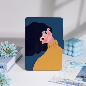 May include: A navy blue tablet case featuring a cartoon illustration of a person with black hair and a yellow sweater. The illustration has a minimalist style with a smiling face. The case is rectangular and has rounded corners.