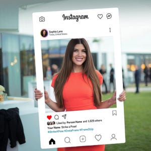 May include: A white Instagram photo booth prop with a white frame and a black and white Instagram logo at the top. The text "Liked by Person Name and 1,629 others" is displayed below the photo frame. The text "Your Name Strike a Pose!" is displayed below the "Liked by" text. The hashtags "#StrikeAPose #InstaFrame #FrameItUp" are displayed below the "Your Name Strike a Pose!" text.
