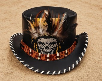 Puede incluir: Sombrero de vaquero negro con diseño de calavera, plumas y una banda decorativa. El sombrero tiene costuras blancas alrededor del borde y probablemente está hecho de cuero. El sombrero tiene un estilo único y atrevido.