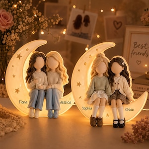 May include: Two illuminated crescent moon figurines featuring pairs of faceless figures sitting together. The left moon displays the names Fiona and Jessica, while the right moon features the names Sophia and Chloe, both decorated with gold star accents.