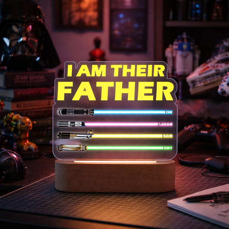 May include: A Star Wars-themed LED lamp with the text "I AM THEIR FATHER" in yellow. The lamp features four lightsaber designs with names below each. The base is made of wood.