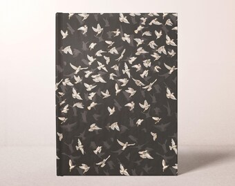 May include: A hardcover journal with a black cover featuring a pattern of white birds in flight. The birds are depicted with detailed wings and are scattered across the cover, creating a sense of movement and freedom.