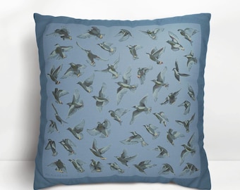 May include: Square throw pillow with a blue background and a pattern of flying birds in shades of gray and white. The pillow has a darker blue border and is likely made of fabric.