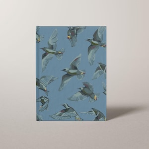 May include: A blue journal featuring a pattern of gray birds in flight. The birds have outstretched wings and are set against a light blue background. The journal is rectangular and stands upright.