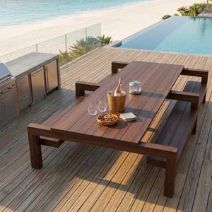 May include: A rectangular dark brown wooden outdoor dining table with two attached benches. The table surface holds a wooden wine bucket with a bottle, two clear glasses, a small bowl of nuts, a folded napkin, and a small metal lantern.