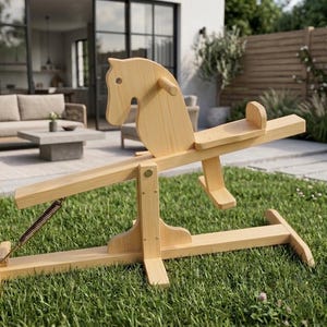 Op de afbeelding: Een wipwap van lichtgekleurd hout met een gestileerd paardenhoofd aan de voorzijde, een centraal draaipunt met een metalen veermechanisme, een vlakke zitting met rugleuning en een stevig onderstel gemaakt van gladde, natuurlijke houten planken.