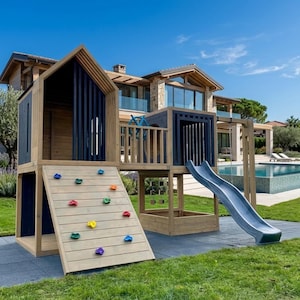 May include: A wooden outdoor play structure featuring a climbing wall with multi-colored handholds, a dark blue vertical slat tower, a central platform with a blue steering wheel, and a gray slide attached to the side on a paved surface.