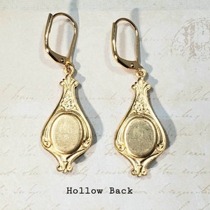 May include: A pair of gold-tone earrings with a hollow back and a decorative design. The earrings have a teardrop shape with a round center.