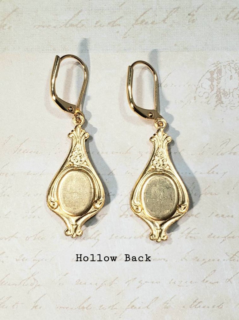 May include: A pair of gold-tone earrings with a hollow back and a decorative design. The earrings have a teardrop shape with a round center.