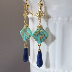 May include: A pair of gold-tone leverback earrings featuring a fan-shaped turquoise bead with gold-tone detailing, suspended from a gold-tone metal accent, and finished with a dark blue teardrop-shaped stone bead at the bottom of each earring.