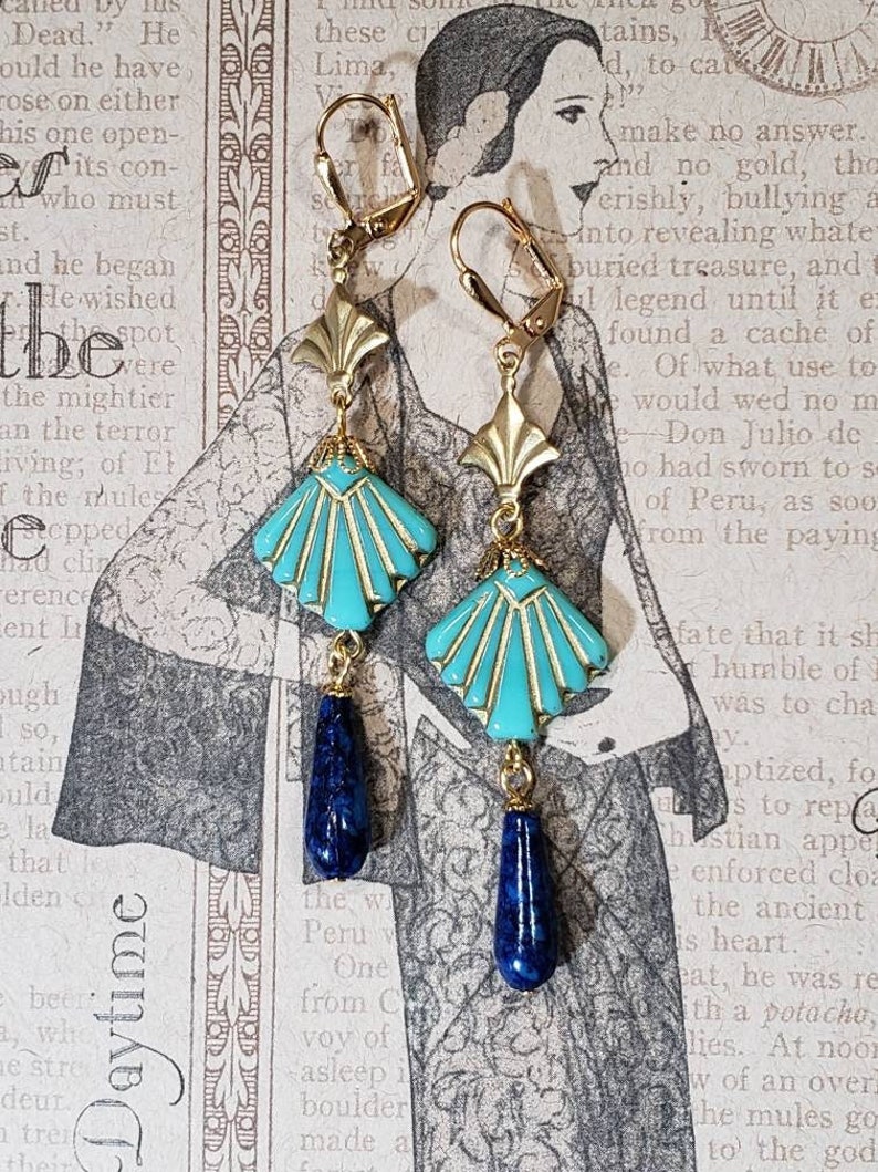 May include: A pair of drop earrings featuring gold-tone lever back hooks, a gold-tone fan-shaped metal component, a turquoise-coloured fan-shaped glass bead with gold-tone inlay, and a dark blue teardrop-shaped stone bead at the bottom.