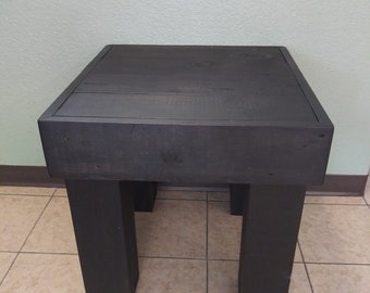May include: A black wooden end table with a square top and four legs. The table is made of reclaimed wood and has a rustic finish.